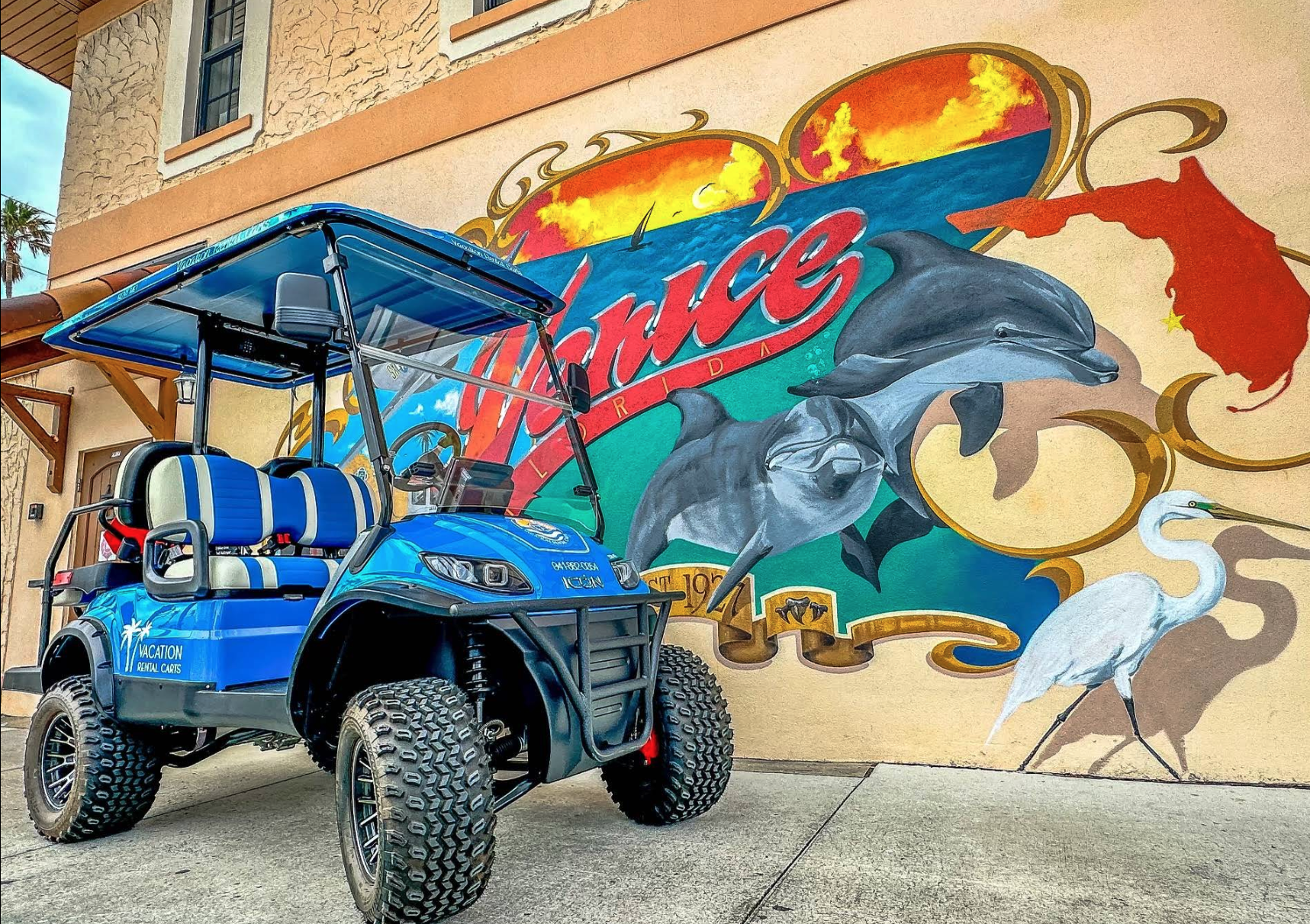 Rental golf cart parked in front of a Venice FL mural.